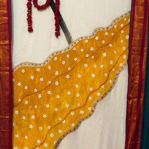 May include: A white fabric backdrop featuring a large, diagonal mustard yellow panel with a white floral pattern and a scalloped gold border. A painted black trident is positioned in the upper left, adorned with a long, vertical red flower garland.