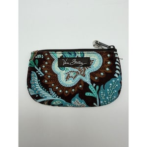 May include: A rectangular coin purse featuring a dark brown background with a light blue and teal paisley pattern. The pouch has a black zipper closure with a metal pull and a rectangular fabric tag with the text Vera Bradley in white script.