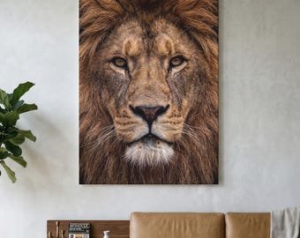 Puede incluir: Una gran impresión de arte mural rectangular que presenta un retrato detallado de frente de un león con una melena marrón gruesa y texturizada y ojos color ámbar. La imagen captura los rasgos faciales del animal, incluida su nariz oscura.