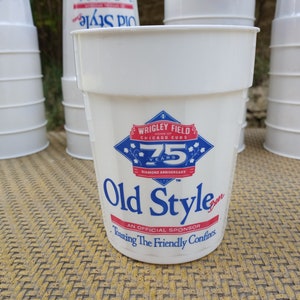May include: White plastic cup with a blue and red logo for Old Style Beer. The logo features the Wrigley Field 75th Diamond Anniversary logo. The text "Wrigley Field, Home of Chicago Cubs, 75 Years, Diamond Anniversary, Old Style, An Official Sponsor, Toasting the Friendly Confines" is printed on the cup.