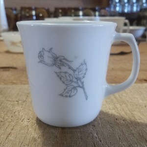 May include: White ceramic mug with a gray floral design of a single rose with leaves.