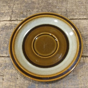 May include: A brown and white ceramic saucer with a ring of brown around the edge.