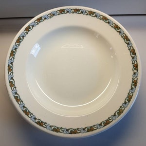 May include: White ceramic soup bowl with a decorative border of brown, green, and blue floral designs.