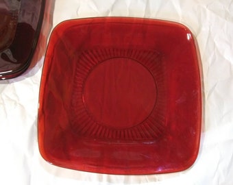 May include: A square, ruby red glass dish with a raised, circular design in the center.
