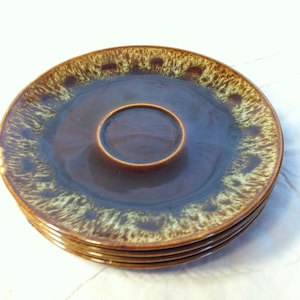 May include: A set of four brown and green ceramic saucers with a ring design around the edge.