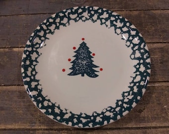 May include: A white ceramic plate with a green and white speckled border. The center of the plate features a dark green Christmas tree with red ornaments.