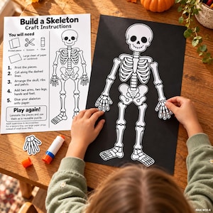 May include: A Build a Skeleton craft activity set featuring a white instruction sheet with black text and a diagram, alongside a black sheet of paper with a white skeleton cutout being assembled. A glue stick and an extra hand cutout are also visible.