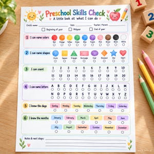 Könnte beinhalten: Ein Preschool Skills Check Bewertungsbogen mit Abschnitten für Farben, Formen, Zählen, Buchstaben, Wochentage und Monate. Das weiße Blatt enthält bunte Illustrationen einer Sonne, eines Apfels und eines Bleistifts sowie Felder für Name, Datum und Lehrer.