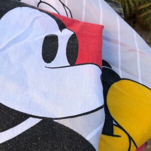 May include: A white, black, and red fabric with a Mickey Mouse design. The fabric is striped and has a red background with a white Mickey Mouse head.