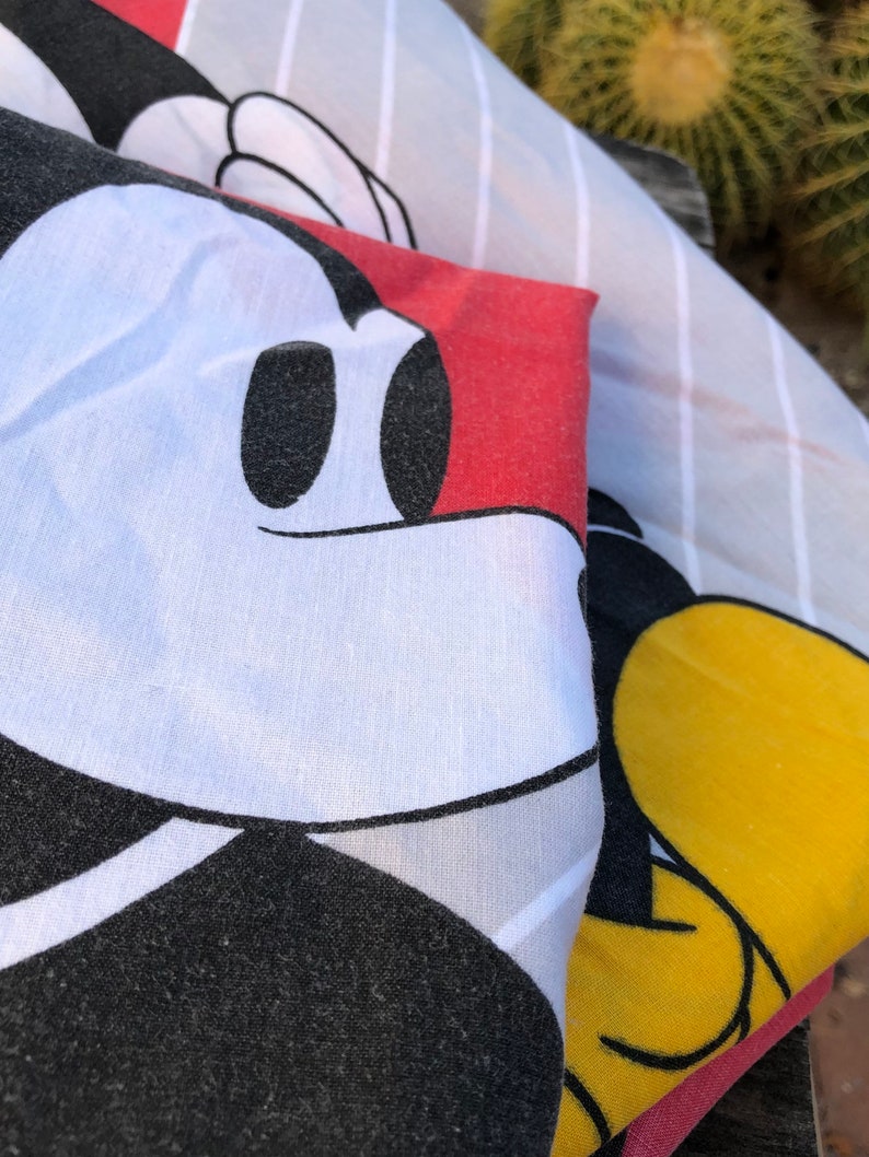 May include: A white, black, and red fabric with a Mickey Mouse design. The fabric is striped and has a red background with a white Mickey Mouse head.