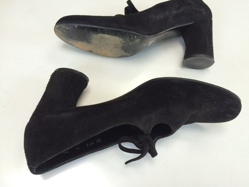 May include: A pair of black suede heeled shoes with a lace-up detail. The shoes have a chunky heel and a rounded toe. The size is marked as "37 2 1/2 37".