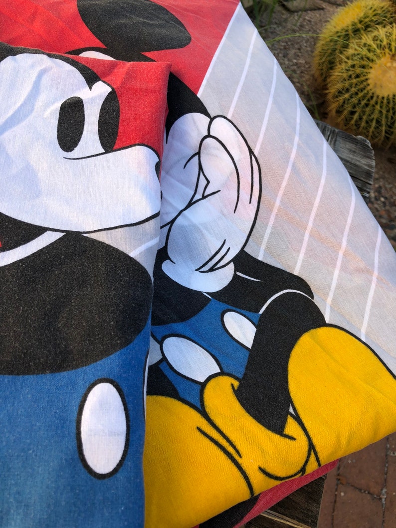 May include: A red, white, and blue Mickey Mouse print fabric. The fabric features a close-up of Mickey Mouse's face and hand.