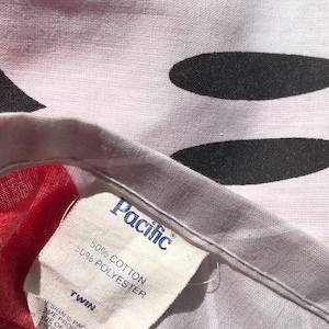 May include: A white twin-sized bed sheet with a black and white Mickey Mouse design. The sheet has a white tag that says "Pacific" and "50% Cotton 50% Polyester".