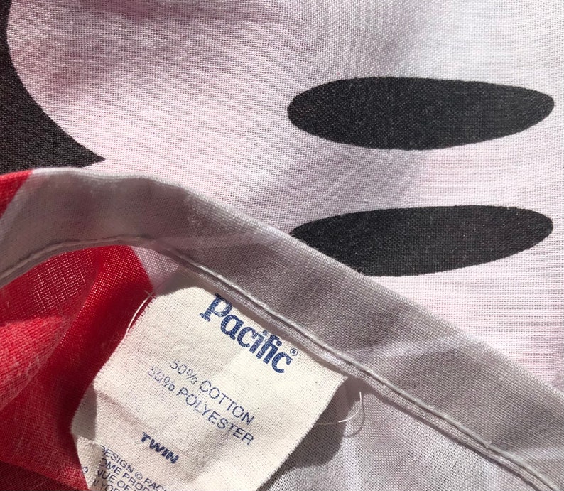 May include: A white twin-sized bed sheet with a black and white Mickey Mouse design. The sheet has a white tag that says "Pacific" and "50% Cotton 50% Polyester".