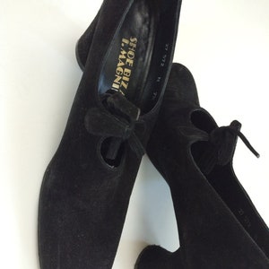 May include: Pair of black suede heeled shoes with a lace-up detail and the text "Shoe Biz I.Magni" on the inside of one shoe. The shoes are size 27 5/2.