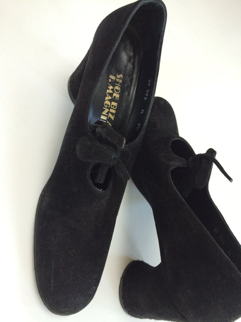 May include: Pair of black suede heeled shoes with a lace-up detail and the text "Shoe Biz I.Magni" on the inside of one shoe. The shoes are size 27 5/2.