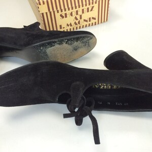 May include: A pair of black suede heeled shoes with a lace-up detail. The shoes are labelled "Shoe Biz at I. Magnin" on the inside.
