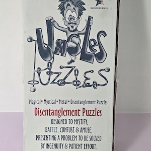 May include: A white rectangular box for Uncle's Puzzles featuring a cartoon character, the text "Uncle's Puzzles," "Magical*Mystical*Metal*Disentanglement Puzzles," and "DESIGNED TO MYSTIFY, BAFFLE, CONFUSE & AMUSE, PRESENTING A PROBLEM TO BE SOLVED BY INGENUITY & PATIENT EFFORT."