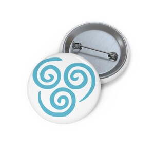 May include: A circular pin-back badge featuring a white background with a light blue graphic design consisting of three interconnected spirals. The back of the badge is made of silver-toned metal and includes a horizontal pin mechanism for attachment.