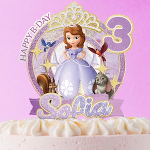 May include: A glittery purple and gold cake topper featuring a cartoon princess in a lavender dress, surrounded by a squirrel, a rabbit, and two birds. The topper includes the text HAPPY B-DAY, the name Sofia, and the number 3 in a large font.