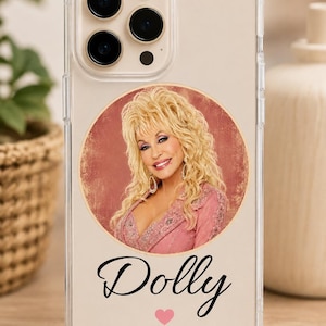 Könnte beinhalten: Eine transparente Smartphone-Hülle mit einem kreisförmigen Porträt von Dolly Parton mit blondem Haar in einem rosa Oberteil. Unter dem Porträt steht das Wort Dolly in schwarzer Schreibschrift, gefolgt von einem kleinen rosa Herzsymbol unten.
