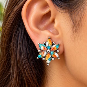 May include: A floral-shaped stud earring featuring marquise-cut stones in vibrant shades of orange, turquoise, and white, set in a polished silver-tone metal frame with small spherical accents between each petal and a central silver bead.