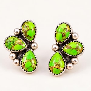 May include: A pair of stud earrings featuring three teardrop-shaped lime green stones with brown matrix patterns, set in silver bezels and accented with small silver spheres arranged in a cluster formation on each earring.