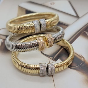May include: Three gold and silver snake chain bracelets with diamond accents. The bracelets are stacked on top of each other.