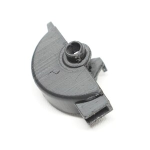 May include: A black, semi-circular plastic component featuring a central cylindrical protrusion with a hollow core, a flat top surface, and a rectangular extension on one side, showing a textured finish consistent with 3D printed manufacturing.