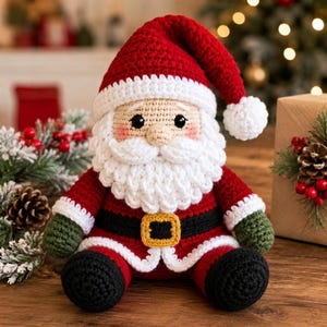 Puede incluir: Un muñeco de Papá Noel tejido a ganchillo con un gorro rojo con pompón blanco, barba blanca, abrigo rojo con ribete blanco, cinturón negro con hebilla amarilla y mangas verde oscuro. El muñeco tiene ojos negros y mejillas rosadas.