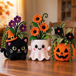 Puede incluir: Tres decoraciones de Halloween tejidas a ganchillo: un gato negro con sombrero de bruja naranja, un fantasma blanco con mejillas rosadas y una calabaza naranja. Cada figura sostiene un ramo de flores tejidas en morado, naranja o negro.