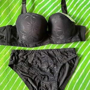 May include: A black matching lingerie set consisting of a molded cup bra with adjustable straps and a floral lace overlay, paired with coordinating high-cut briefs featuring a central floral lace panel and solid black side sections.