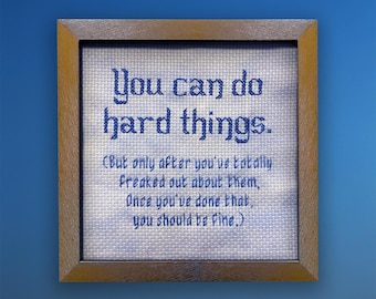 May include: Cross-stitched artwork in a wooden frame. The text reads "You can do hard things." Below, smaller text says, "(But only after you've totally freaked out about them. Once you've done that, you should be fine.)"