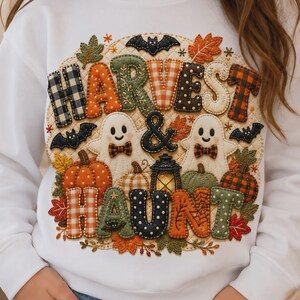 May include: A white long-sleeve sweatshirt featuring a colorful graphic print with the text HARVEST & HAUNT. The design includes two white ghosts, pumpkins, bats, and autumn leaves in various patterns like plaid, polka dots, and stripes.