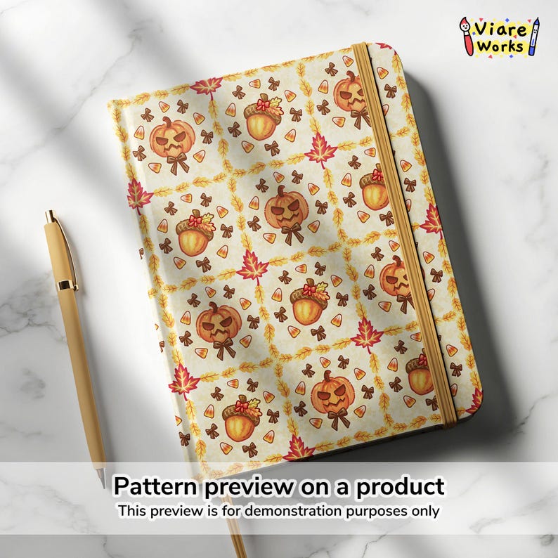 May include: A notebook featuring a repeating autumn pattern of orange jack-o'-lantern pumpkins, brown acorns, red maple leaves, and yellow candy corn on a cream background, secured with a vertical tan elastic band, accompanied by a tan pen.