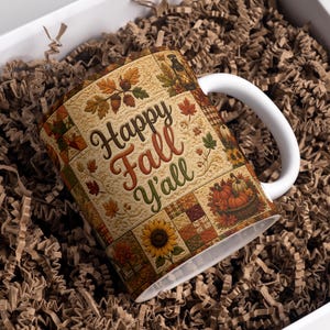 May include: A white ceramic mug featuring a patchwork-style design with autumn motifs including orange pumpkins, sunflowers, acorns, and fall leaves. The text "Happy Fall Y'all" is printed in the center in a brown and green script font.