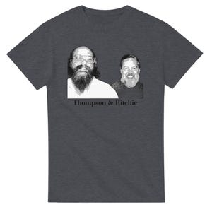 May include: A charcoal gray short-sleeve t-shirt featuring a black and white graphic print of two bearded men with glasses. Below the portrait, the text "Thompson & Ritchie" is printed in a bold, black, serif font centered on the chest area.