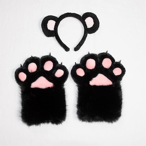 Può includere: Un set composto da un cerchietto nero con due orecchie arrotondate con centri rosa e due guanti a forma di zampa in peluche nero con cuscinetti rosa e piccoli artigli neri su ogni dito, realizzati in materiale morbido e soffice.