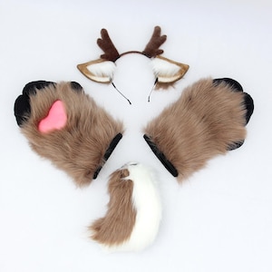 Peut inclure: Un ensemble d'accessoires en fausse fourrure comprenant un serre-tête avec des bois et des oreilles de cerf marron, deux gants en forme de patte marron avec bordure noire et un coussinet rose en forme de cœur, et une queue en fausse fourrure.