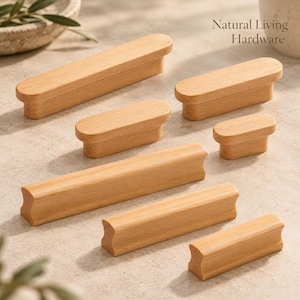 Puede incluir: Una colección de siete tiradores de madera de color claro en varias longitudes, con extremos redondeados y superficies lisas. El texto Natural Living Hardware es visible en la esquina superior derecha, presentado en una fuente serif simple.
