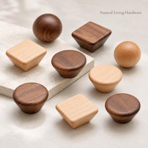 May include: A collection of wooden cabinet knobs in various shapes including spheres, squares, and circles, featuring light and dark wood tones. The text Natural Living Hardware is visible in the upper right corner of the image.