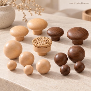 Puede incluir: Una colección de pomos de madera para armarios en varios tamaños y formas, incluyendo madera clara lisa, madera oscura y un pomo con una parte superior de ratán trenzado. El texto Natural Living Hardware es visible en la esquina superior derecha.