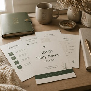 May include: An ADHD Daily Reset Toolkit printed on off-white paper with dark green text and leaf graphics. The set includes sheets titled Focus Reset, Energy Check-in, Brain Dump, and Evening Reset, alongside a green planner and a ceramic mug.