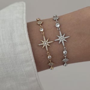 Peut inclure: Deux bracelets à chaîne délicats ornés d'un motif central en forme d'étoile incrusté de pierres claires. Un bracelet est doré et l'autre est argenté. Les deux modèles présentent de petites étoiles et des pierres rondes le long de la chaîne.