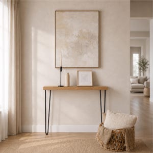 May include: A rectangular wooden console table with four black metal hairpin legs. On the table sits a tall black candle holder with a thin taper candle, a beige ceramic vase, and a small square framed print featuring a delicate leaf sketch.