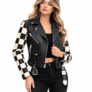 May include: A black leather motorcycle jacket featuring long sleeves with a cream and black checkered pattern. The jacket includes a notched lapel, silver-toned metal zippers on the front, a small flap pocket, and an adjustable belt at the waist.