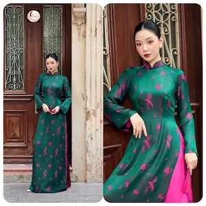 Könnte beinhalten: Ein langärmeliges smaragdgrünes Kleid mit Stehkragen und einem sich wiederholenden magentafarbenen Blumenmuster. Das Kleidungsstück hat Seitenschlitze, die eine einfarbige magentafarbene Unterschicht freilegen und einen Lagen-Look erzeugen.