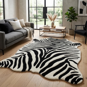 May include: An area rug featuring a black and white zebra stripe pattern. The rug has an irregular, organic shape that mimics the outline of an animal hide, with a thick, textured pile that creates a high-contrast visual effect on the floor.