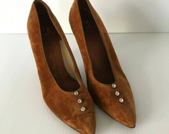 Peut inclure: Une paire d'escarpins en daim marron à bout pointu. Chaque chaussure comporte trois petits strass étincelants près de l'orteil. Les talons mesurent environ 7,6 cm de haut.
