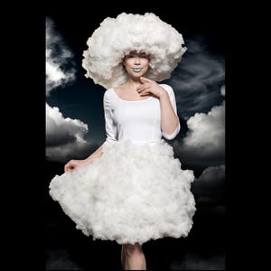 Puede incluir: Un vestido blanco que presenta una falda voluminosa similar a una nube y un tocado grande y redondeado a juego con forma de nube. El corpiño es ajustado con mangas tres cuartos y escote redondo, contrastando con el material blanco y esponjoso.